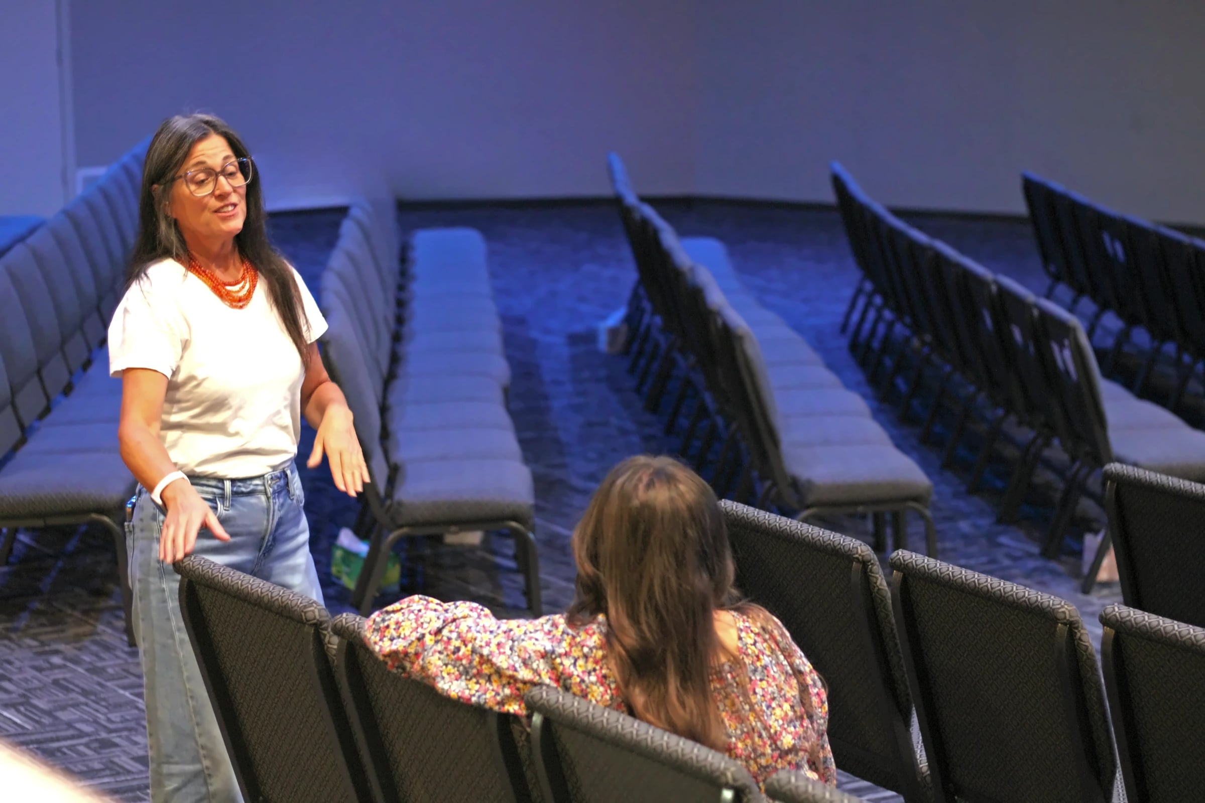 A woman welcomes a visitor among the empty rows of the sanctuary.